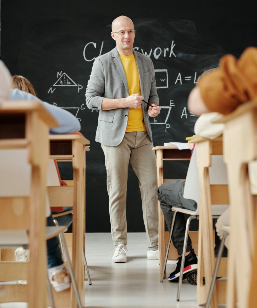 Lehrkraft vor Klasse aus Perspektive von Schülerinnen und Schülern